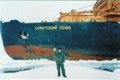 This is a photo of a scientist who is standing on the ice in front of the icebreaker 'Soviet Union'